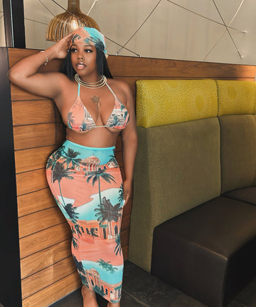 Woman wearing a colorful outfit with palm tree design in an indoor setting.